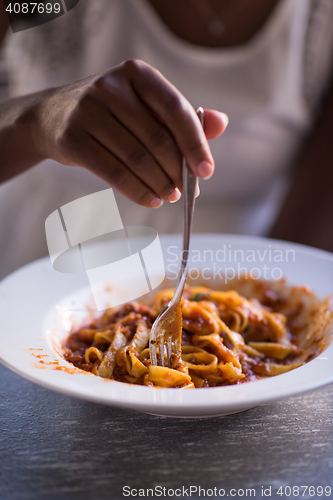 Image of a young African American woman eating pasta
