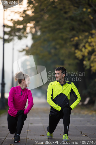 Image of a young couple warming up before jogging