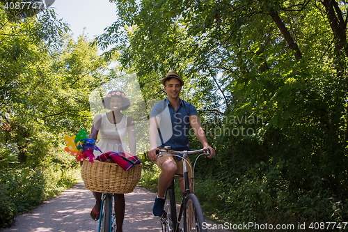 Image of Young multiethnic couple having a bike ride in nature