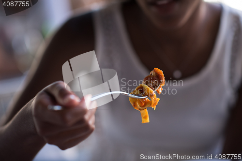 Image of a young African American woman eating pasta