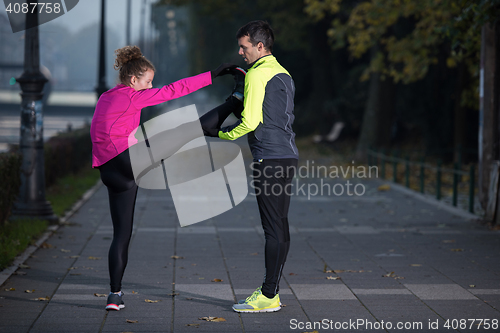 Image of a young couple warming up before jogging