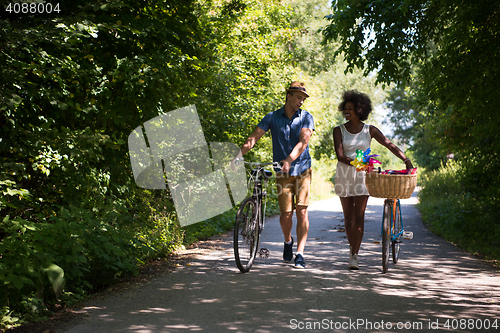 Image of Young multiethnic couple having a bike ride in nature