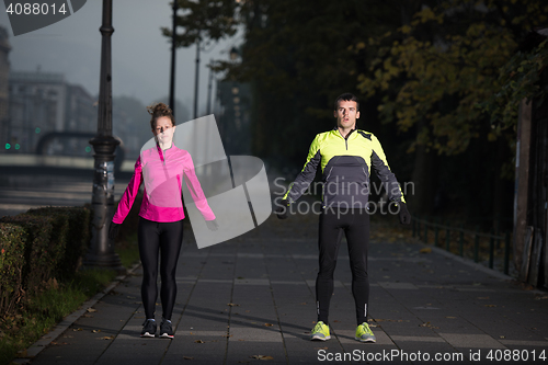 Image of a young couple warming up before jogging