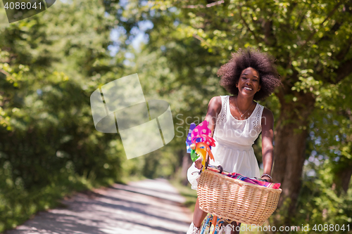 Image of pretty young african american woman riding a bike in forest