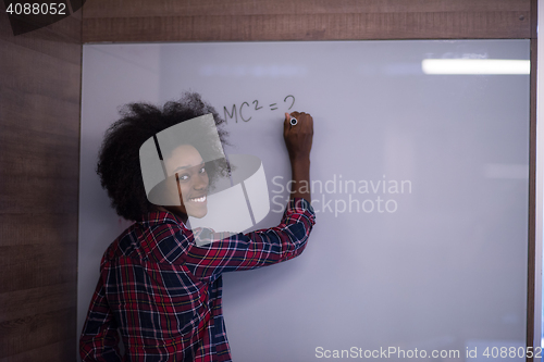 Image of African American woman writing on a chalkboard in a modern offic