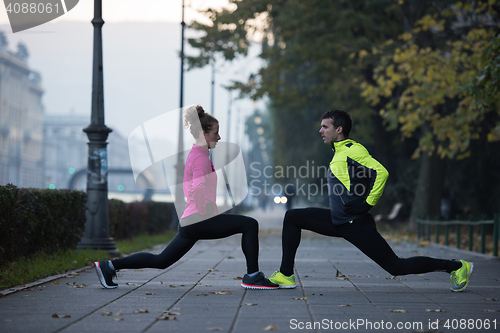 Image of a young couple warming up before jogging