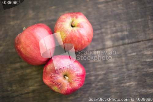 Image of Three red apples on wooden table