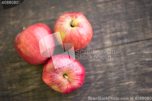 Image of Three red apples on wooden table