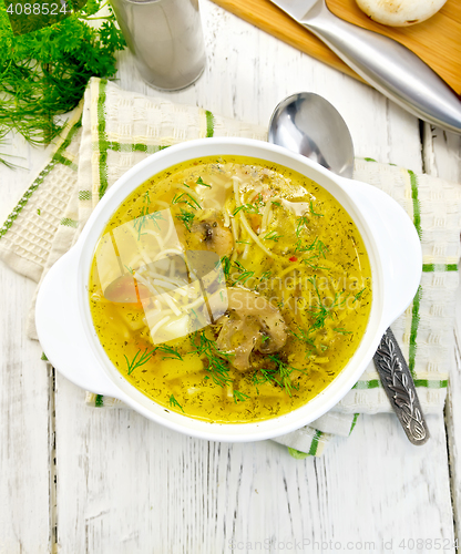 Image of Soup with champignons and noodles in bowl on light board top