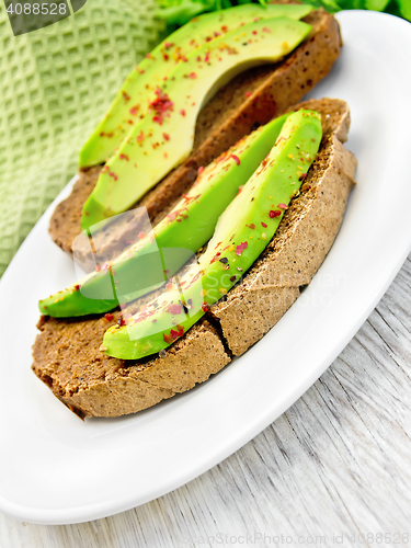 Image of Sandwich with avocado and pepper in dish on board