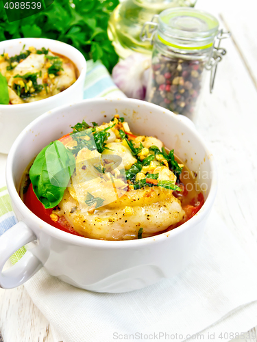 Image of Fish baked with tomato and garlic in white bowl on board