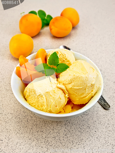 Image of Ice cream apricot in white bowl on table with spoon