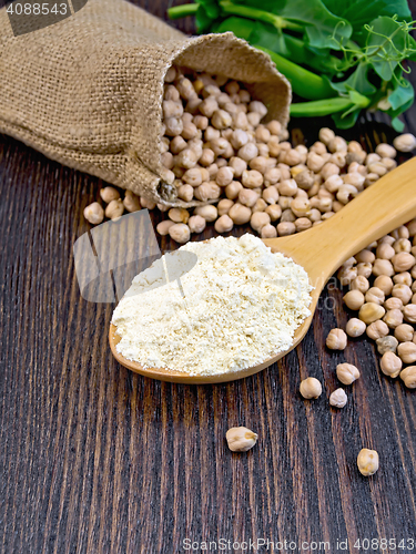 Image of Flour chickpeas in spoonful with peas on dark board