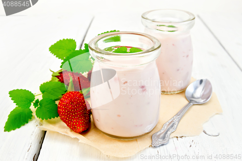 Image of Yogurt with strawberries in jar on parchment and board