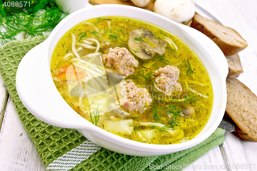 Image of Soup with meatballs and noodles in bowl on green napkin