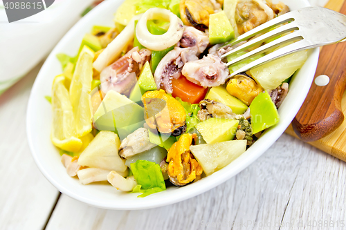 Image of Salad with seafood and lemon in plate on white board