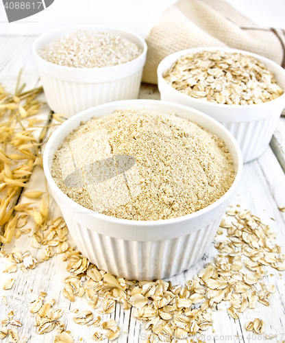 Image of Flour oat in white bowls with bran and flakes on board