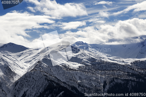 Image of View on snow mountains and cloudy sky in sun evening