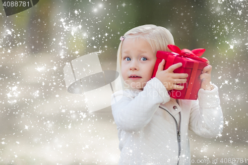 Image of Baby Girl Holding Red Christmas Gift Outdoors with Snow Effect