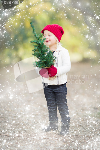 Image of Baby Girl In Mittens Holding Small Christmas Tree with Snow Effe