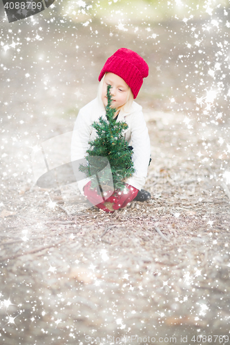 Image of Girl In Red Mittens and Cap Near Small Christmas Tree with Snow 