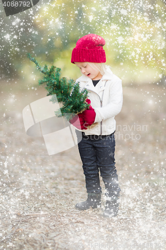 Image of Baby Girl In Mittens Holding Small Christmas Tree with Snow Effe