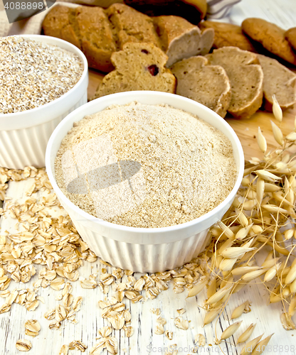 Image of Flour oat and bran in white bowl with bread on board