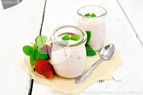 Image of Yogurt with strawberries in jar on paper and board