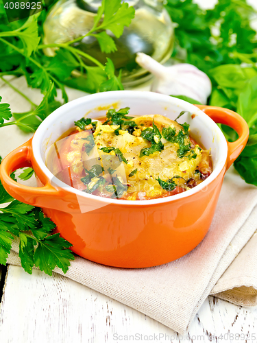 Image of Fish baked with tomato in red pot on light board