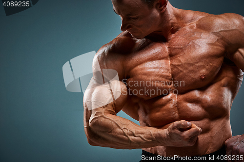 Image of torso of attractive male body builder on gray background.