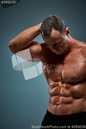 Image of torso of attractive male body builder on gray background.