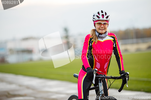 Image of Young smiling athletic female cyclist in special suit and helmet