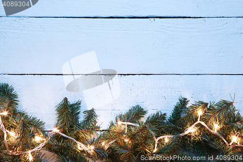 Image of Christmas fir tree with yellow lightbulb on wooden board background