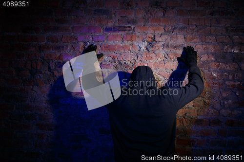 Image of Gunman against wall at night