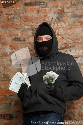 Image of Robber in mask with banknotes