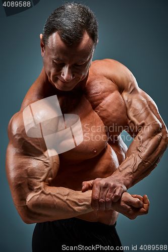 Image of torso of attractive male body builder on gray background.