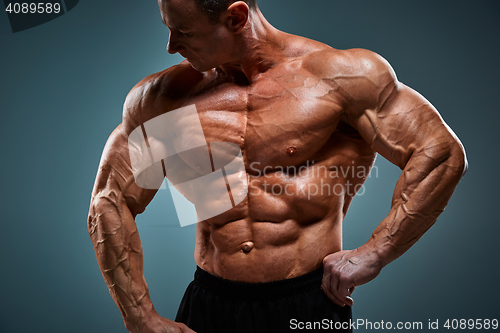 Image of torso of attractive male body builder on gray background.