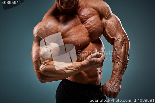 Image of torso of attractive male body builder on gray background.