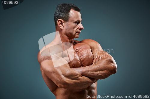 Image of torso of attractive male body builder on gray background.