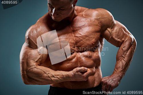 Image of torso of attractive male body builder on gray background.