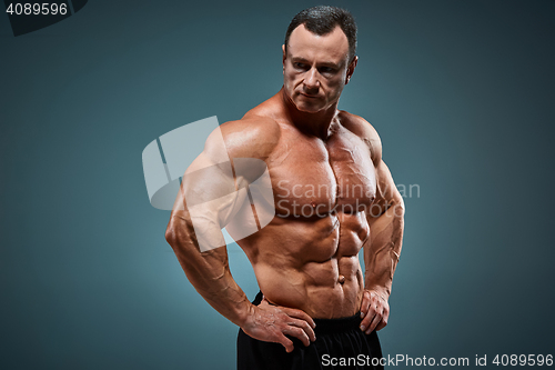 Image of torso of attractive male body builder on gray background.