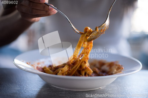 Image of a young African American woman eating pasta