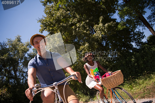 Image of Young multiethnic couple having a bike ride in nature