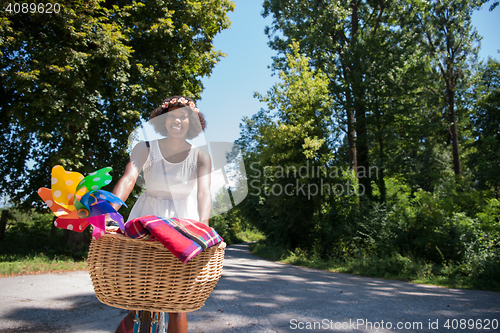 Image of pretty young african american woman riding a bike in forest