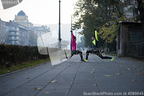 Image of a young couple warming up before jogging