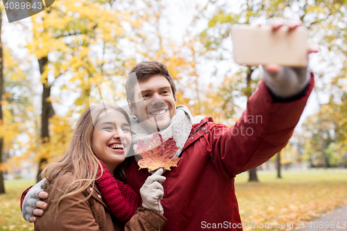 Image of couple taking selfie by smartphone in autumn park