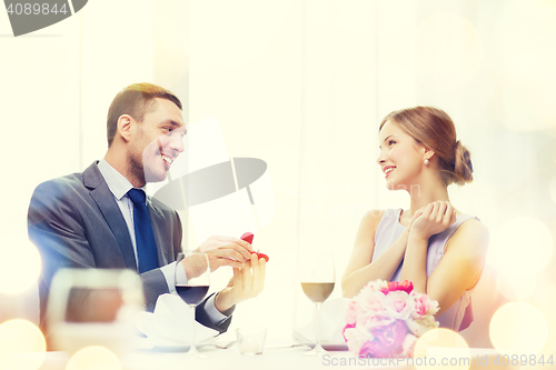 Image of man proposing to his girlfriend at restaurant