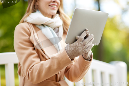 Image of close up of woman with tablet pc in autumn park