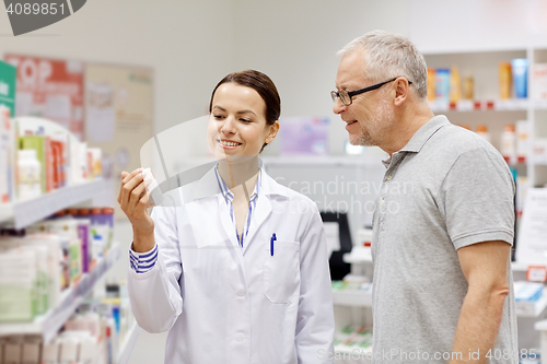 Image of pharmacist showing drug to senior man at pharmacy