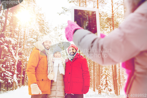 Image of smiling friends with tablet pc in winter forest